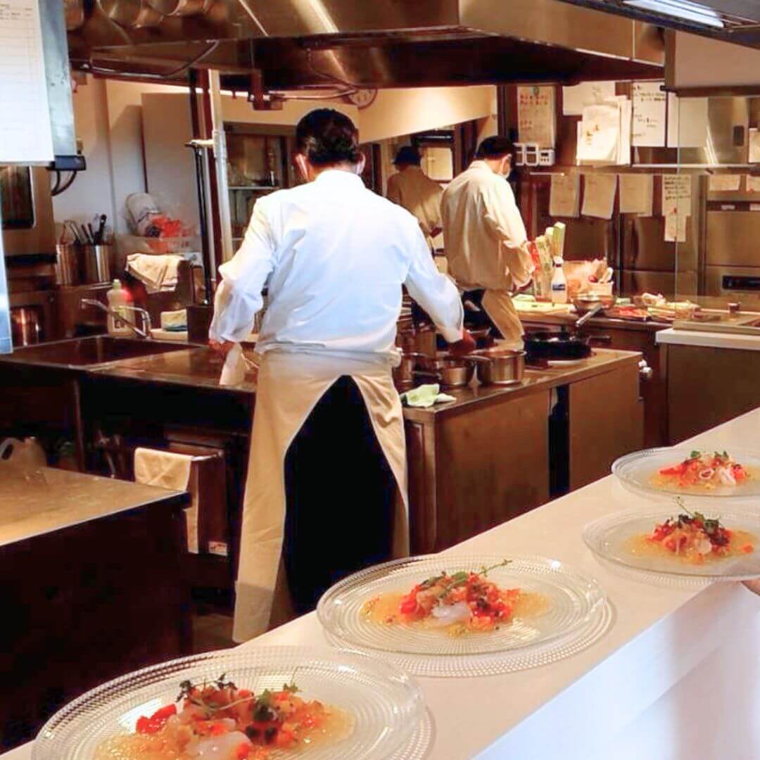 リゾートホテルの厨房で料理を盛り付ける調理スタッフ