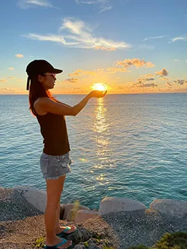 夕日を背景に写真を撮る女性